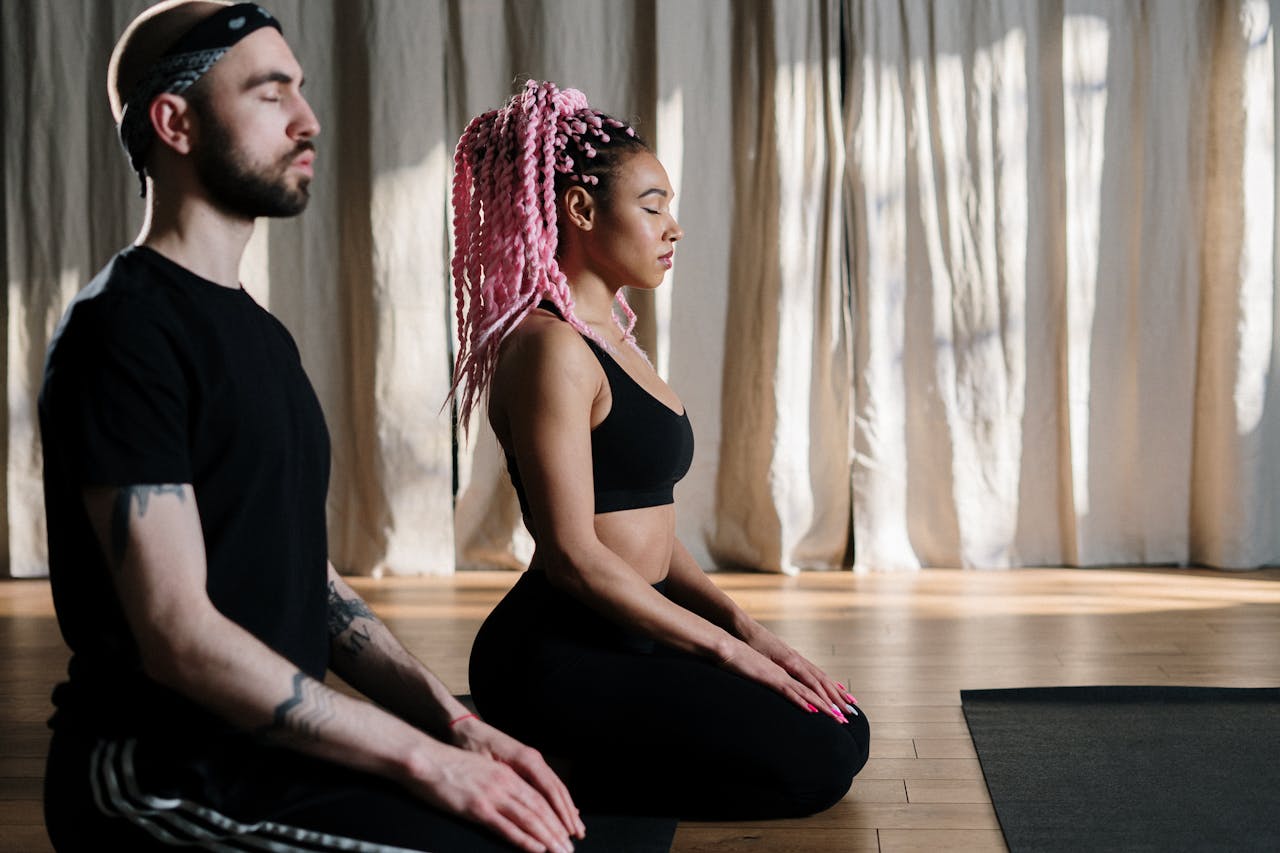 Two adults meditate in a serene yoga studio, embracing holistic wellness.